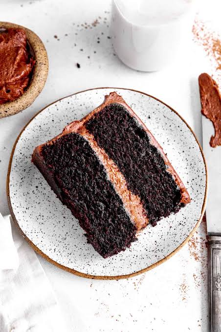 A slice of rich vegan chocolate cake on a ceramic plate.